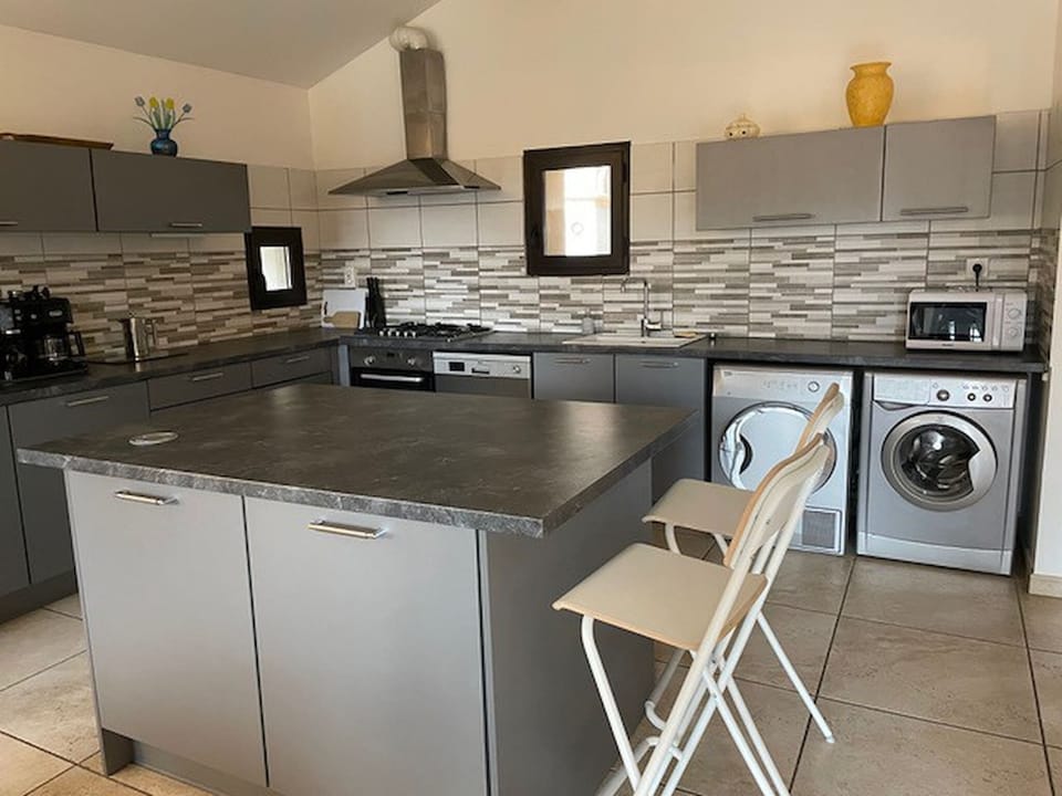 Large, fully-equipped kitchen with washing machine and tumble dryer. With space for dining, a large dining table for 8 or the bar for smaller meals.