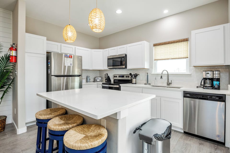 Your modern kitchen awaits with gleaming appliances, warm pendant lights, and a breakfast bar perfect for morning coffee or evening conversations.
