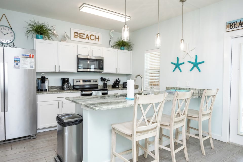 Your bright beach-themed kitchen features modern appliances, granite counters, and coastal charm perfect for cooking vacation meals together.