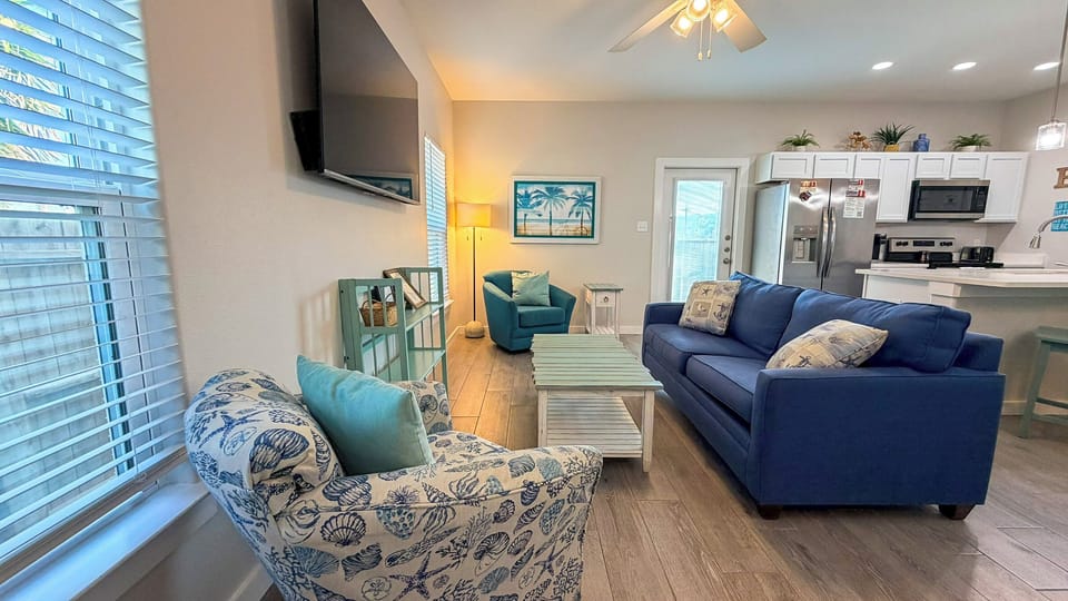 Relax in your bright, coastal-themed living space featuring a comfortable navy sofa and charming seashell-patterned chair.