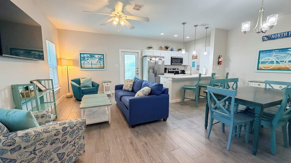 Relax in your bright, coastal-themed living space with comfy seating, modern kitchen, and cheerful blue accents that create the perfect beach getaway vibe.