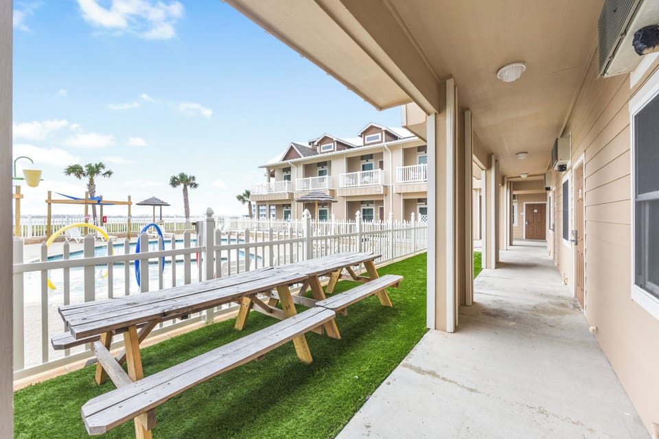 Covered walkway and courtyard area with picnic tables and playground equipment visible in a residential complex.