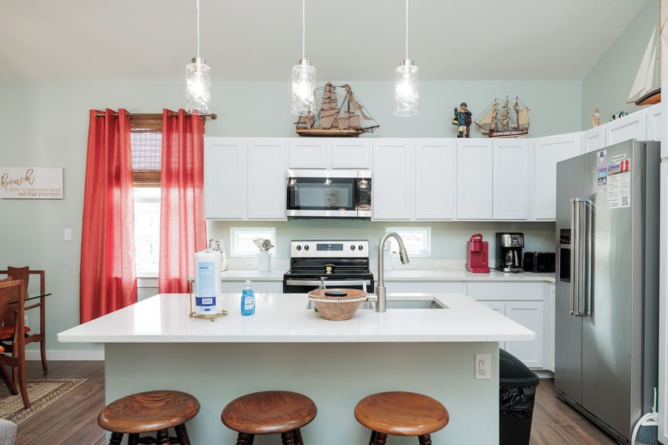 Your fully equipped kitchen awaits with modern appliances, coastal charm, and a breakfast bar perfect for morning coffee together.