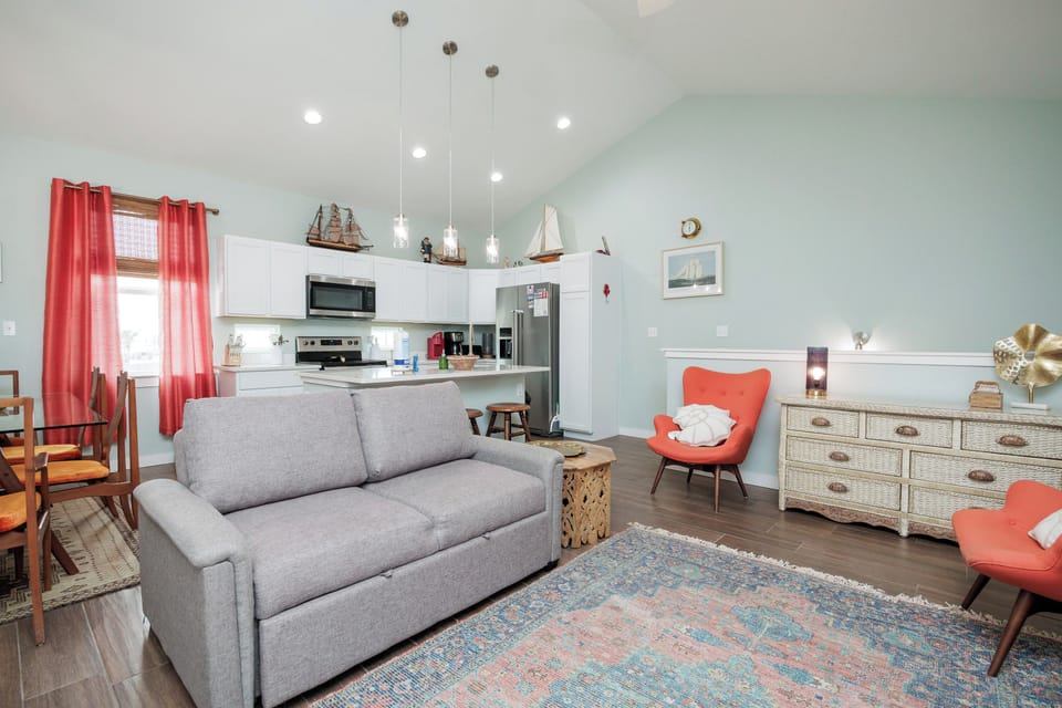 Unwind in your stylish open-concept retreat with comfortable seating, modern kitchen, and charming nautical touches that create the perfect coastal getaway atmosphere.