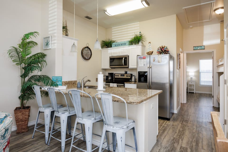 Your open kitchen invites you to gather around the granite island with coastal-style bar stools, perfect for morning coffee or casual meals together.