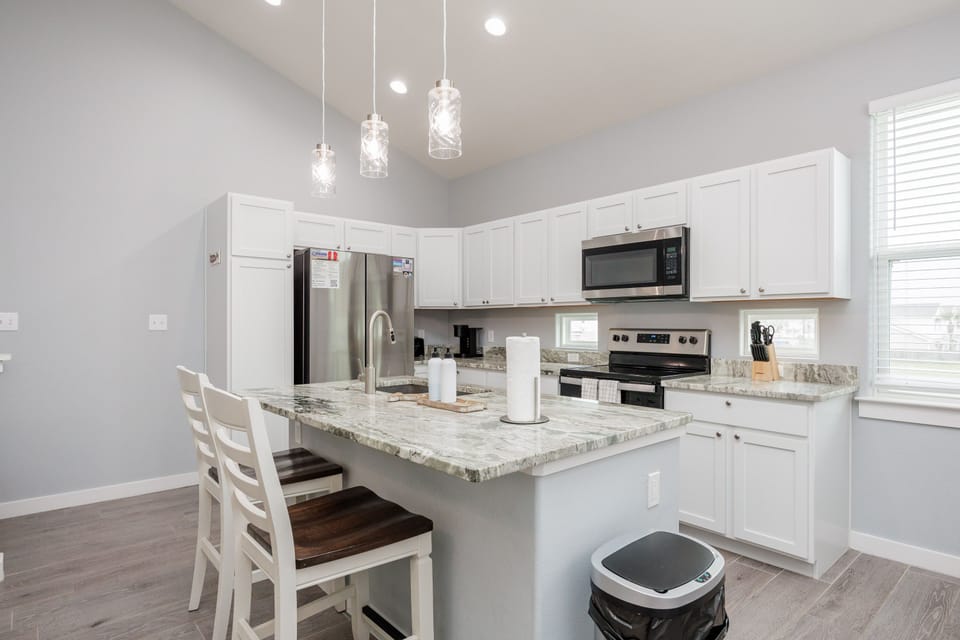 Cook your favorite meals in this bright, fully equipped kitchen with granite countertops, stainless steel appliances, and elegant pendant lighting.