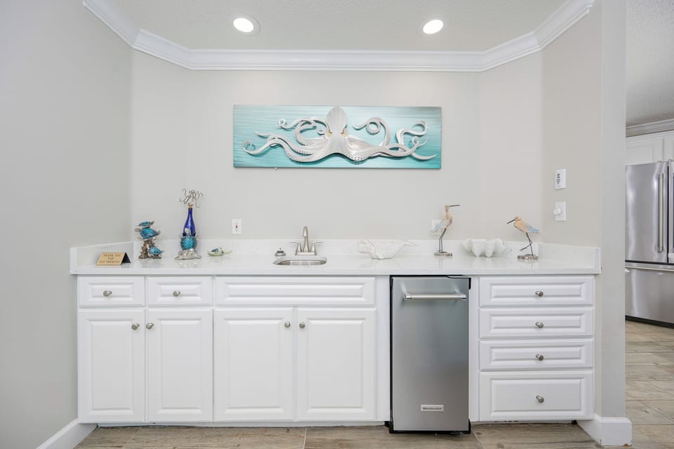 Craft a refreshing drink at the sleek bar area, enhanced by artistic coastal decor
