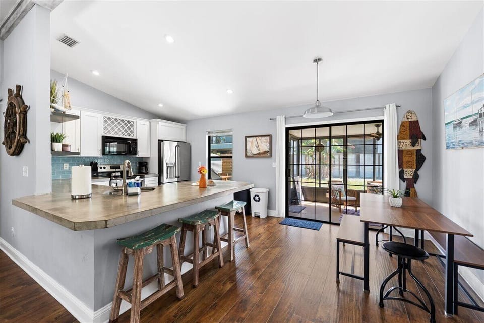 Open kitchen and dining area with island seating and access to screened patio.
