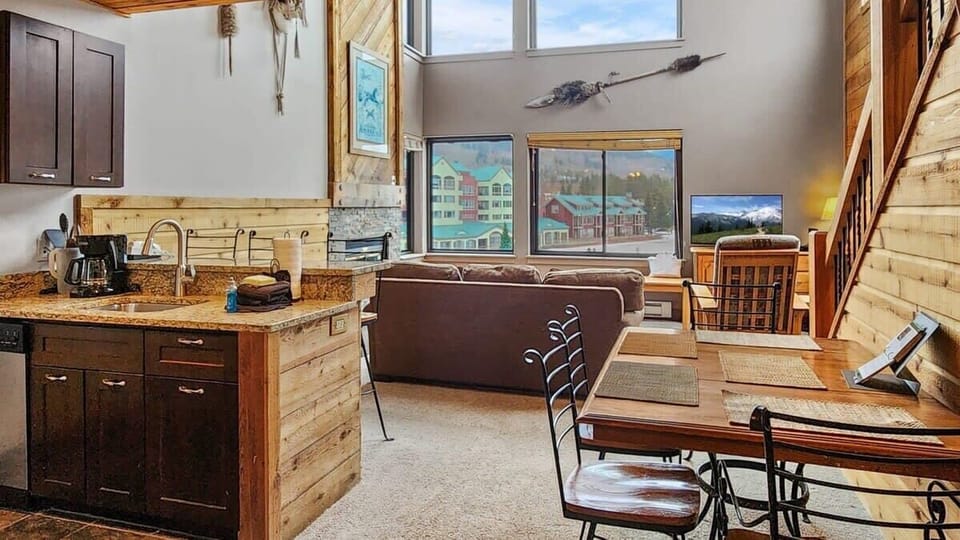 The main living space features a kitchen/dining/living room in an open-layout, boasting high ceilings and large windows framing the gorgeous lake view.