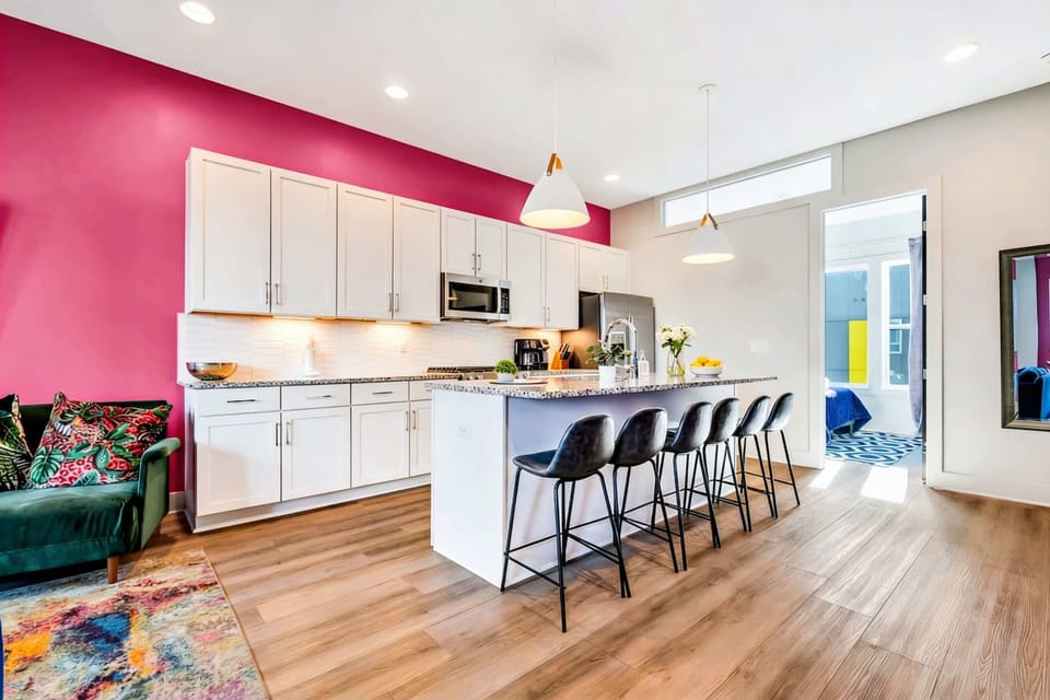 Kitchen island with bar stools and a magenta accent wall. The cook is never left out when everyone else is gathered around eating and laughing