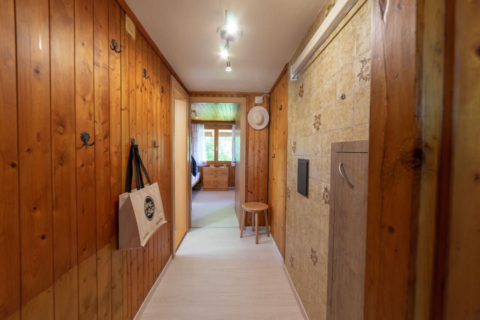 Wood-panelled hallway with a coat rack and decorative wall design
