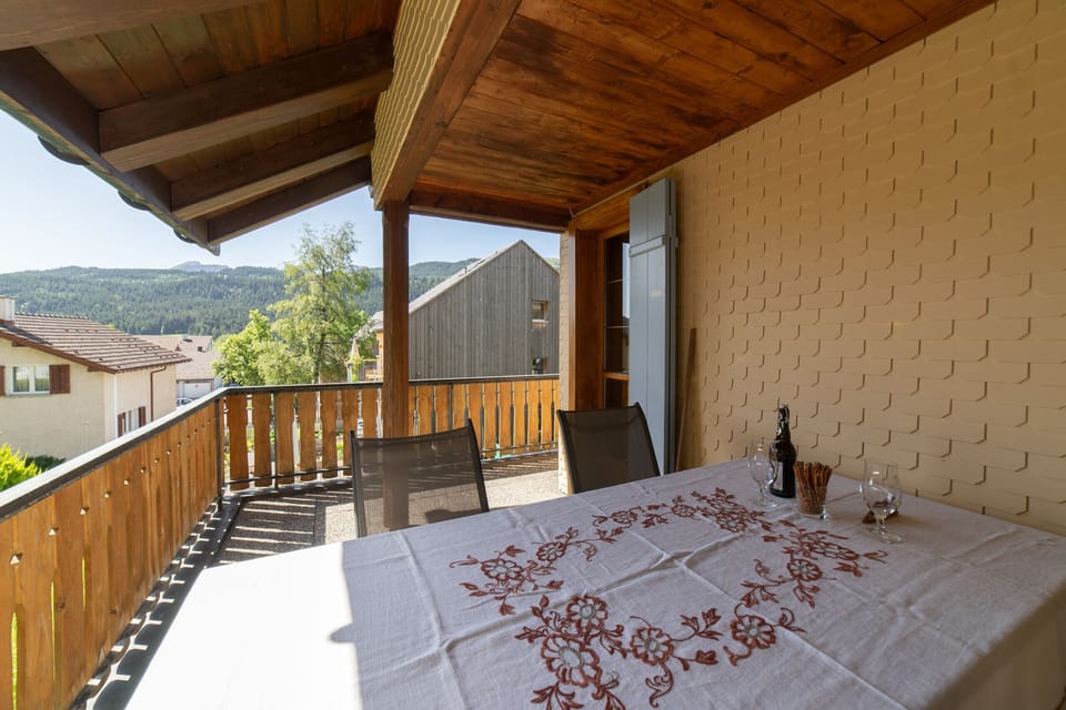 A covered balcony with a dining table and views of the countryside
