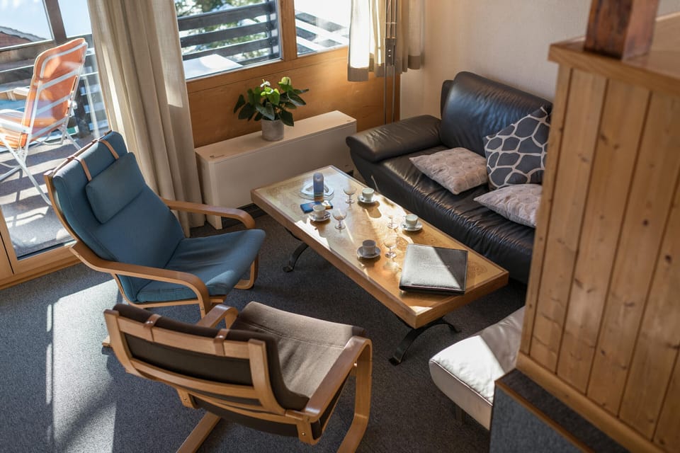 Bright living area with sofa, armchairs and balcony access