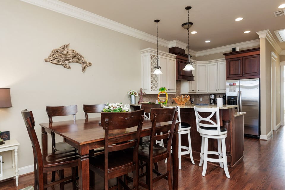 Your open-concept kitchen and dining space blends rich wood with coastal charm, creating the perfect spot to gather for meals.