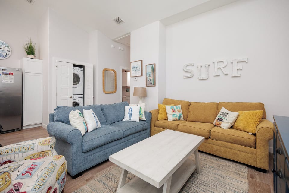 Sink into plush sofas in your bright living space, where colorful pillows and beachy vibes create the perfect atmosphere for relaxation.