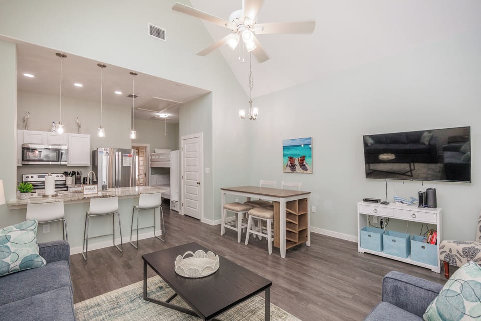 Relax in your open-concept living space with modern kitchen, dining area, and cozy seating—perfect for unwinding after beach adventures.