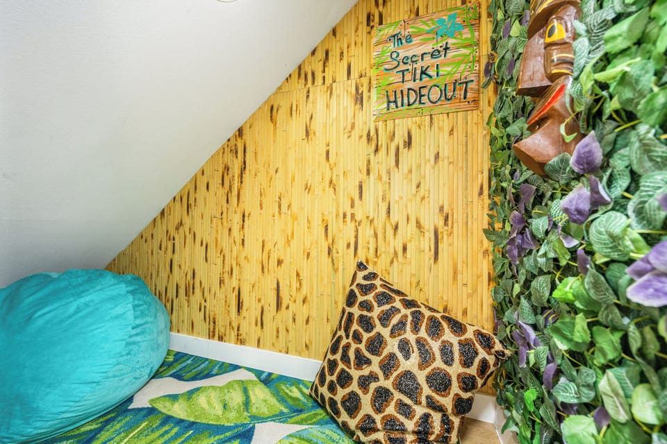 Escape to your tropical hideaway with vibrant tiki decor, bamboo walls, and lush greenery creating the perfect island paradise.