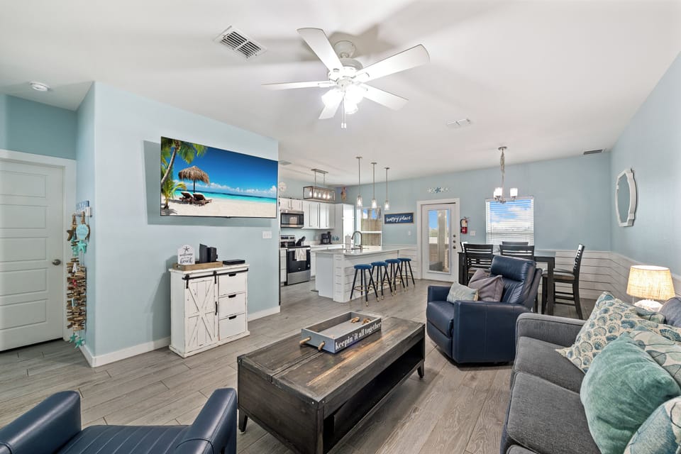 Soothing blue walls and modern beach-house charm create the perfect coastal retreat. This open-plan space flows effortlessly from living to dining to kitchen, ideal for gathering and unwinding.