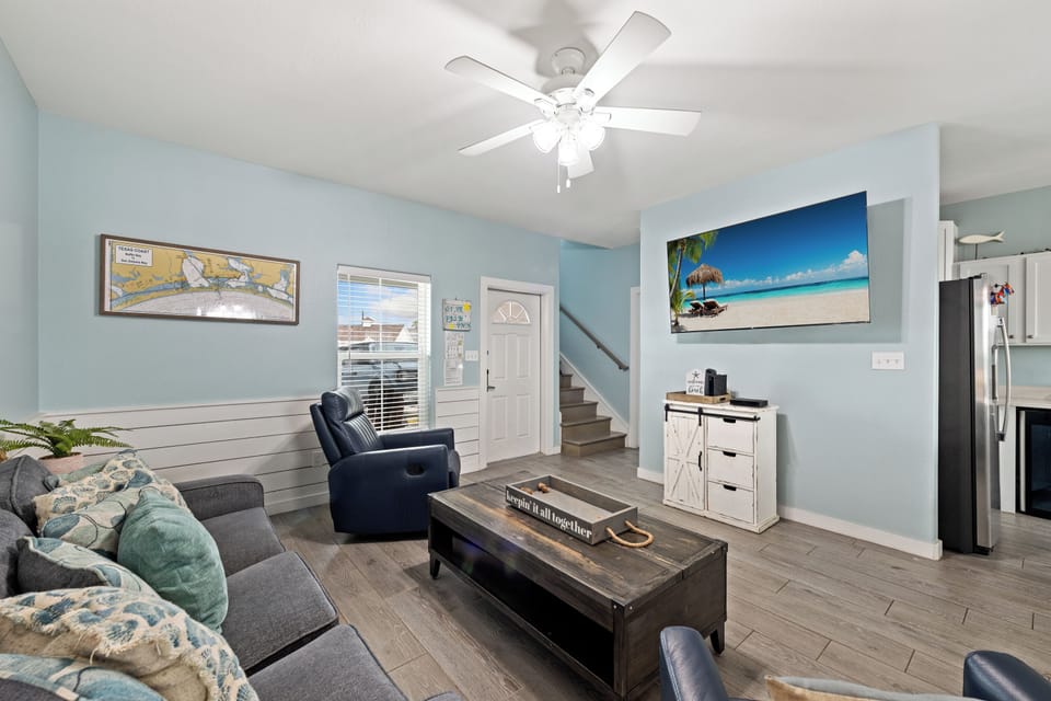 Settle into your living room's coastal calm, where soft blue walls and natural light create the perfect backdrop for unwinding after beach days.
