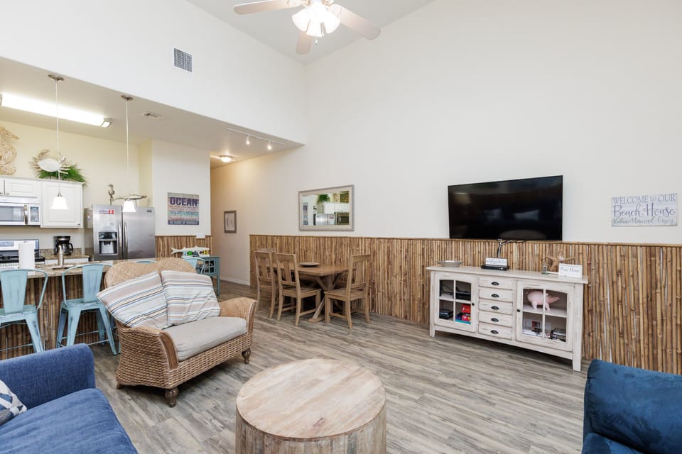 Relax in your coastal-inspired open living space featuring bamboo accents, comfortable seating, and a fully equipped kitchen for memorable beach house gatherings.