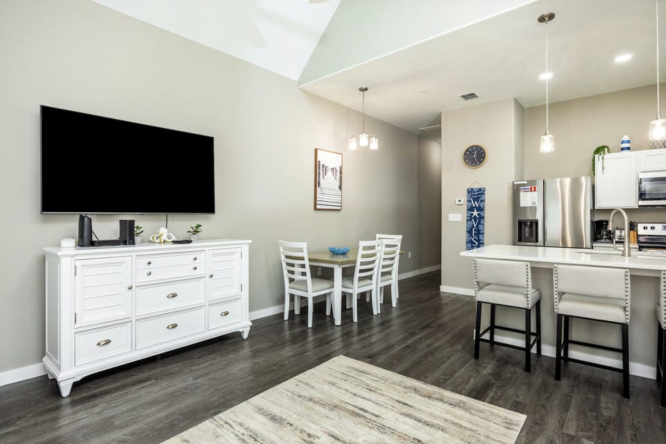 Your spacious open-plan living area features a large TV, modern kitchen with island seating, and bright dining nook perfect for morning coffee.