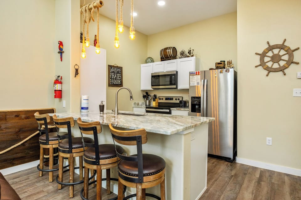 Gather around your nautical-themed kitchen island with its stunning marble countertop and rope pendant lights creating the perfect coastal ambiance for cooking and socializing.