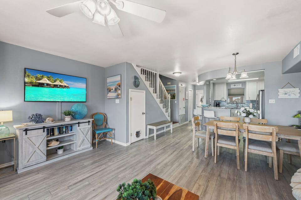 You'll love this bright, open-concept living space where soft gray walls meet warm wood-tone floors. Gather around your dining table steps from the fully equipped kitchen, or relax in the cozy living area complete with coastal charm and modern entertainmen
