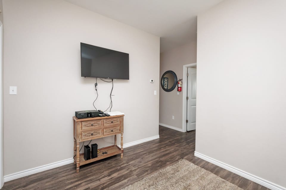 Unwind in your cozy entertainment space with a large flat-screen TV and charming wooden console for all your relaxation needs.