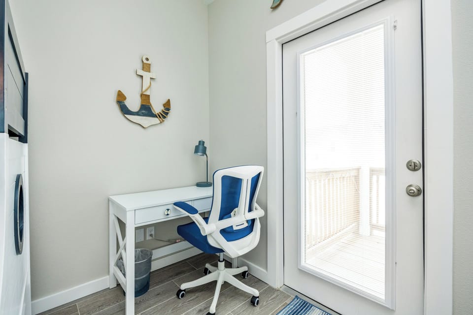 Your bright workspace corner features a modern desk and ergonomic chair, perfect for catching up on work while coastal breezes drift through the door.