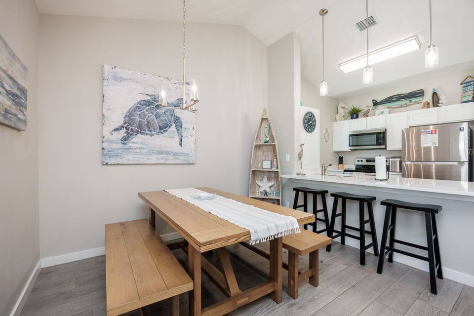 Your coastal kitchen flows seamlessly into the dining space, where ocean-inspired art sets the perfect mood for memorable meals.