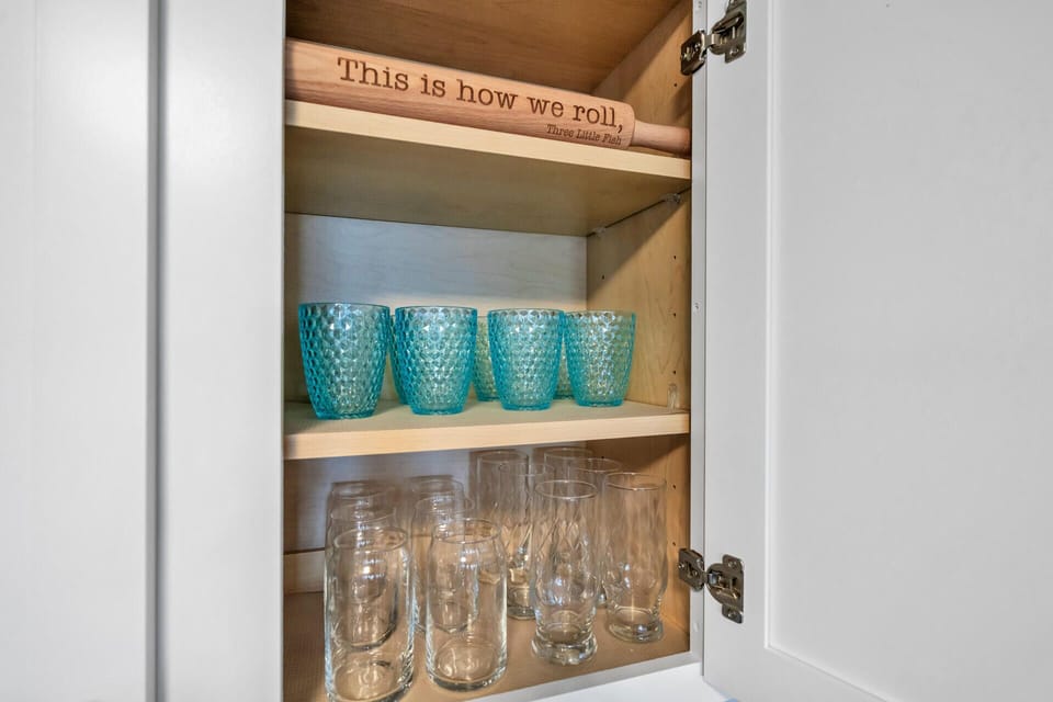 Your well-stocked cabinet holds colorful glasses and drinkware, making it easy to serve refreshing beverages during your stay.