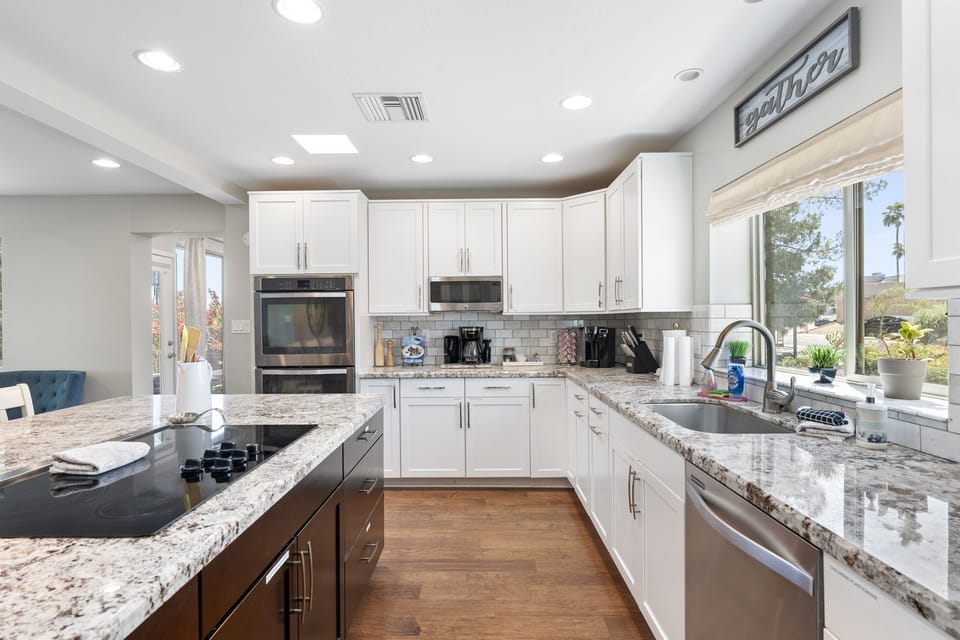 Kitchen is well lit with skylights and picture window. Convection dual ovens, dishwasher, electric stove, side-by-side refrigerator, coffee stations, large granite island, and hardwood floors.