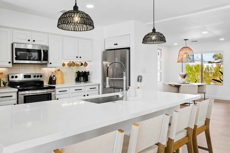 Fully-stocked kitchen with stainless steel appliances and island with barstool seating for four