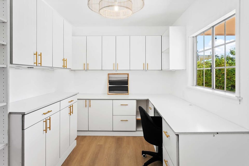 Office with storage cabinets, desk, under cabinet lighting, views of the backyard, bookcase