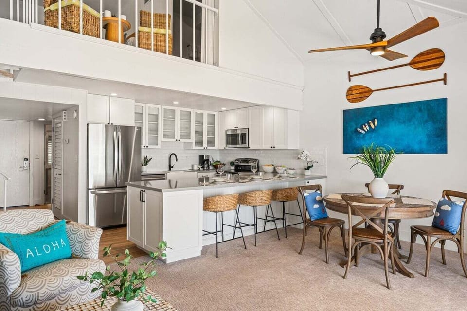 Fully updated kitchen with sleek white cabinetry, breakfast bar seating, and easy flow to the dining space