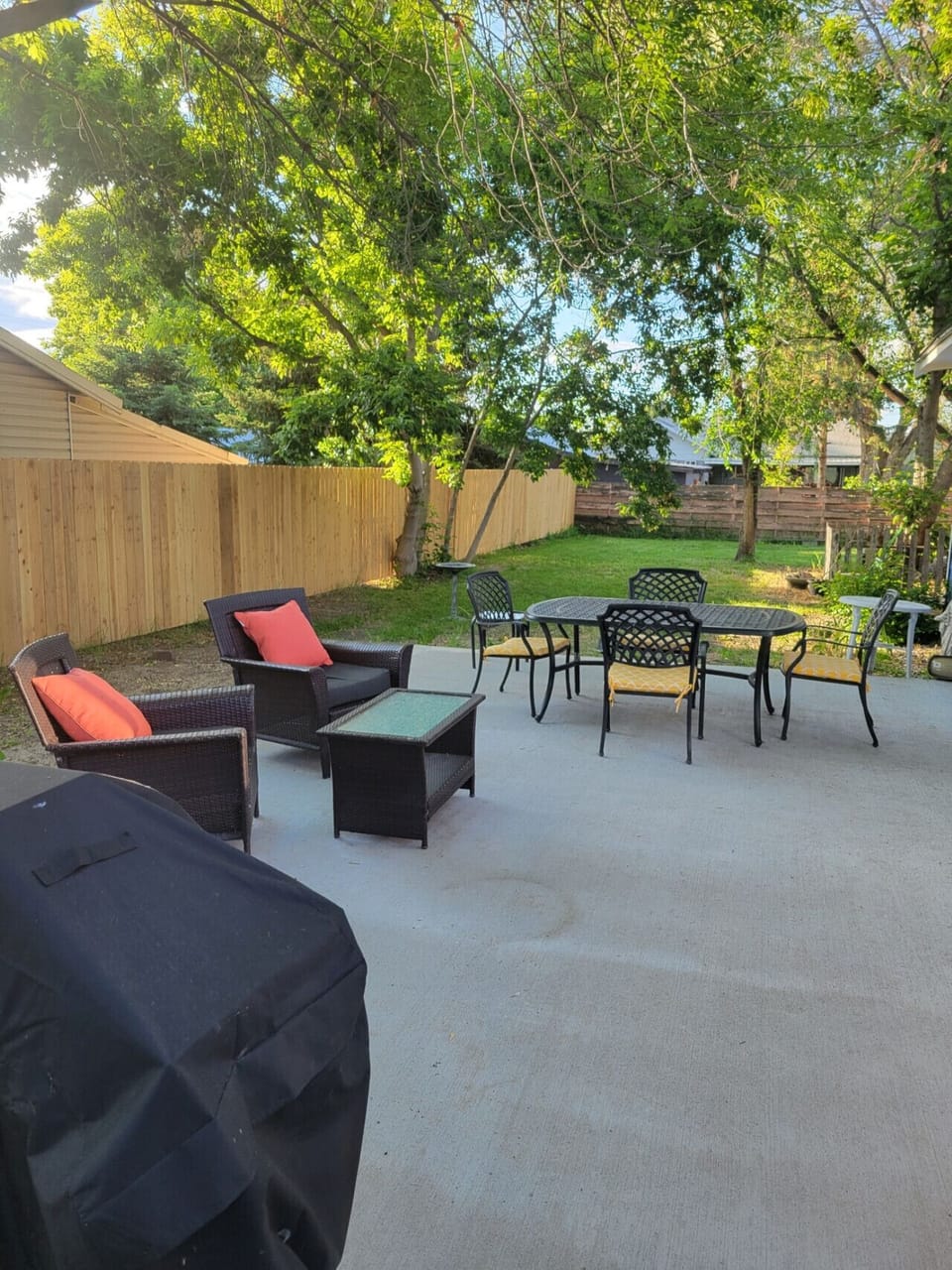 Spacious fenced backyard patio with comfortable seating-ideal for outdoor dining and relaxing.