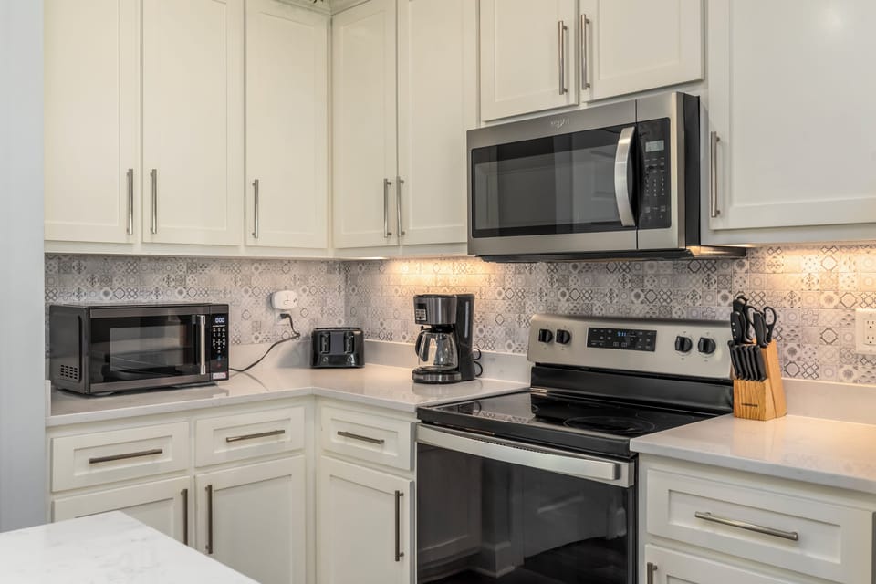 Your fully equipped kitchen features white cabinetry, stainless appliances, and elegant backsplash—perfect for cooking memorable meals during your stay.