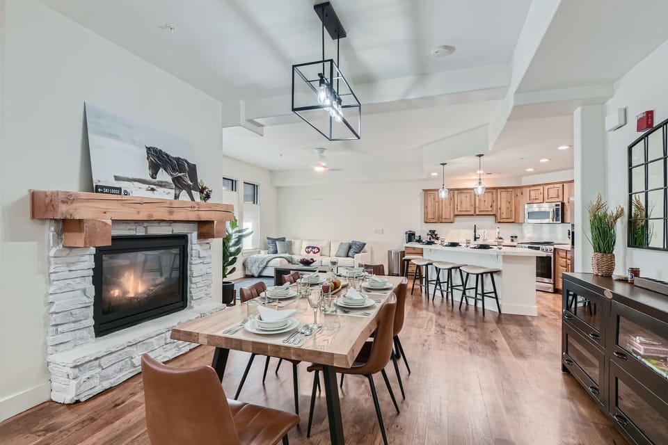 Open-concept great room featuring a cozy fireplace, stylish dining area, and fully equipped kitchen. Perfect for entertaining, with modern finishes, ample seating, and mountain-inspired design—ideal Park City vacation living.