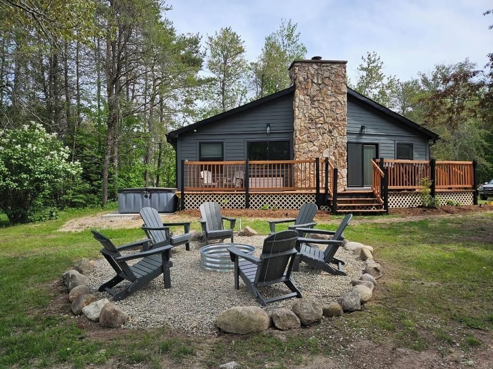 Backyard with comfy Adirondack chairs and hot tub to the left of home.