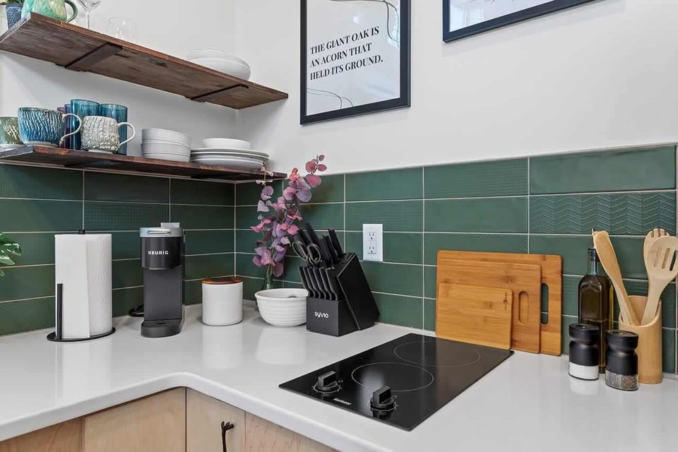Enjoy the convenience of a well-stocked cooking area with a sleek cooktop, Keurig coffee maker, knife set, cutting boards, olive oil, and seasonings—all ready for your culinary needs.

