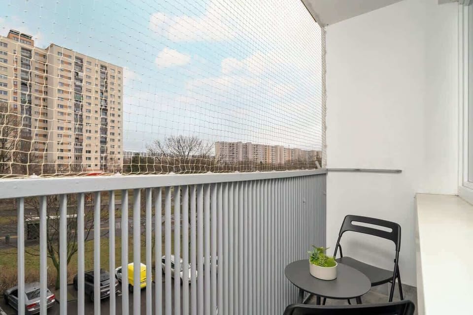 A balcony with a grey railing, minimalist outdoor seating, and a scenic urban view, offering a peaceful and relaxing outdoor space.
