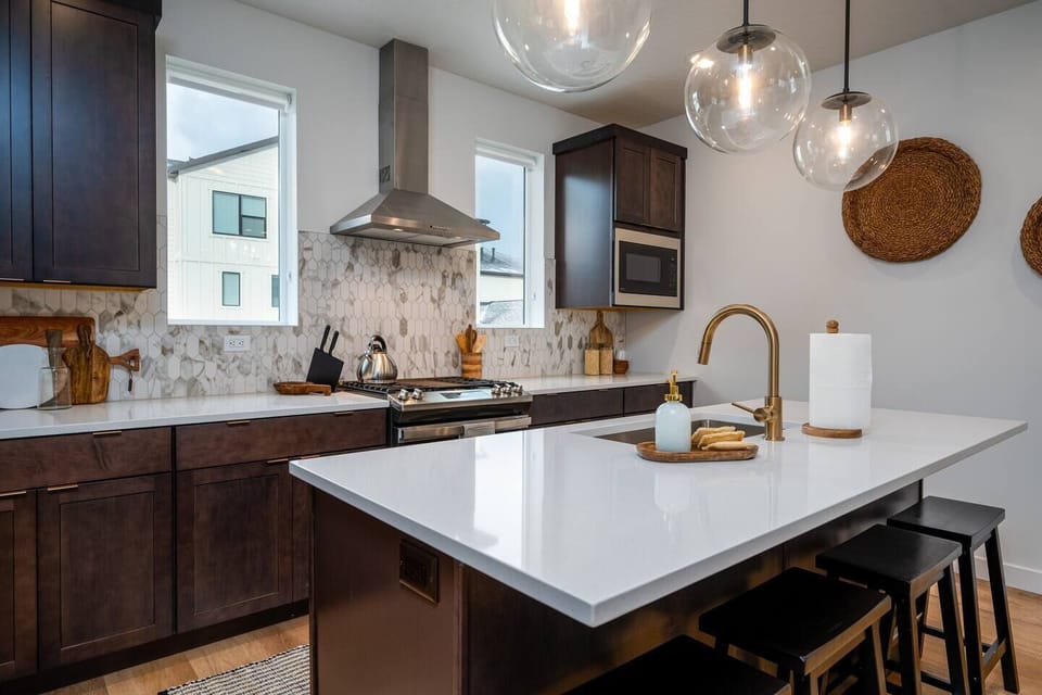 The gourmet kitchen features an island with seating for four and is equipped with brand-new stainless steel appliances, including a microwave, gas stove, and spacious refrigerator.