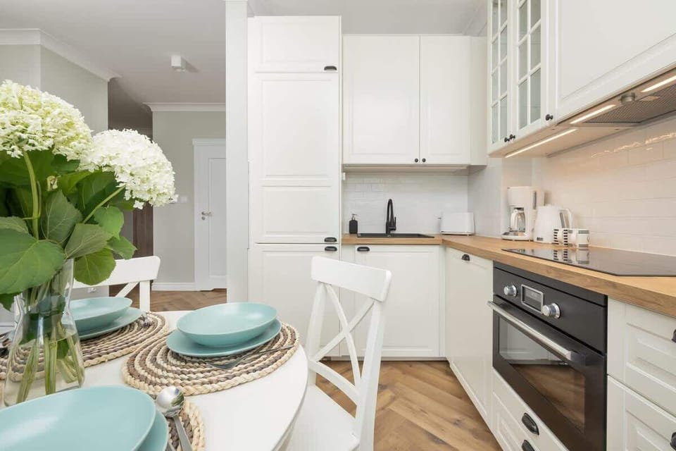 A beautifully set dining area with blue accents, fresh flowers, and elegant white furniture.

