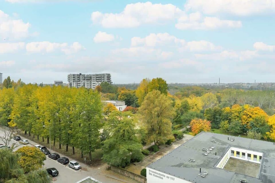 A wider perspective of the surrounding area, filled with greenery, buildings, and a clear sky.


