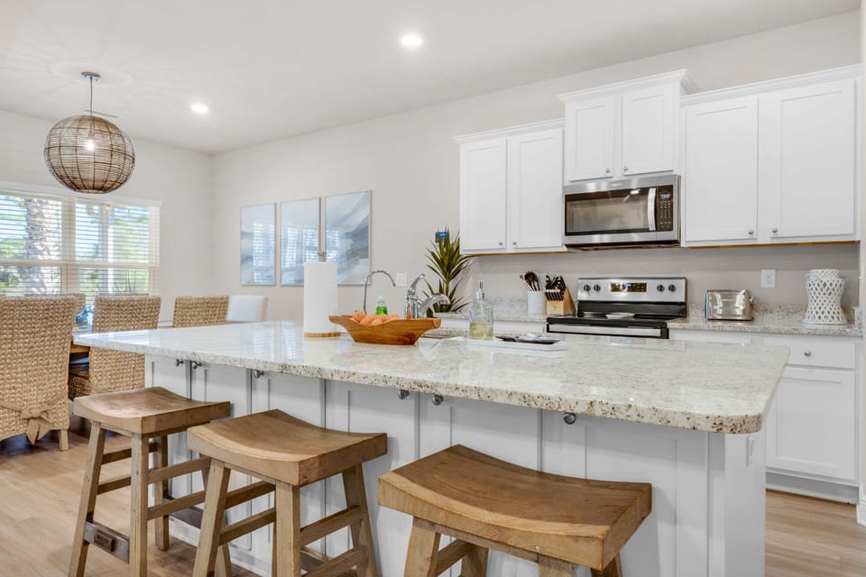 Modern kitchen with large granite island and barstool seating.