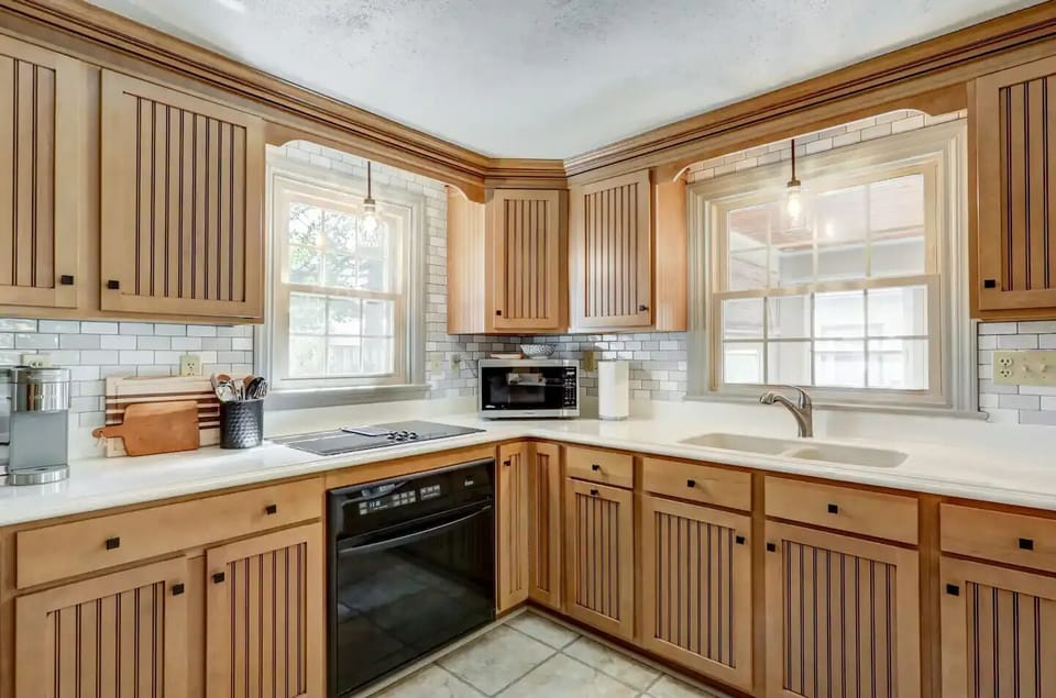 Kitchen with electric stove, oven, refrigerator, microwave and basic cookware.