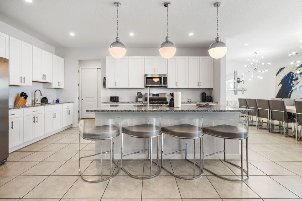 Fully equipped kitchen with granite counters, stainless appliances, and island seating for four.