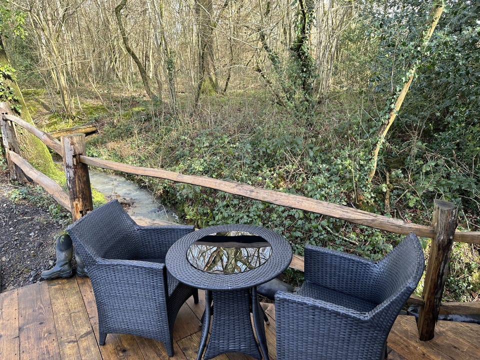 Bistro table on outside decking with the stream babbling alongside the barn 