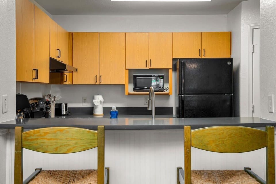 Functional kitchen with wooden cabinetry and a breakfast bar for casual dining.