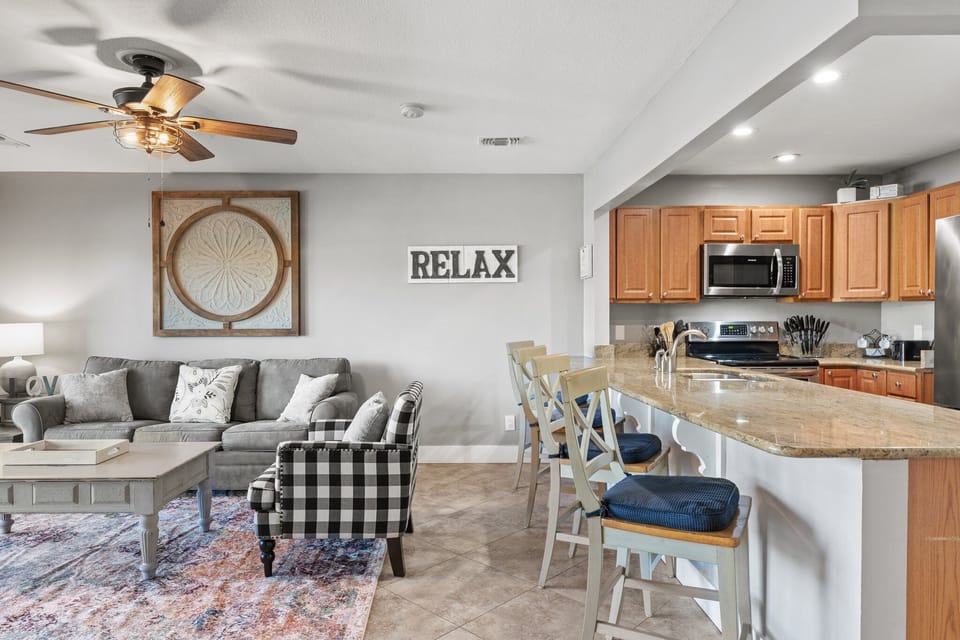 Open-concept living and kitchen area with coastal décor, bar seating, and plenty of space to relax after a beach day.